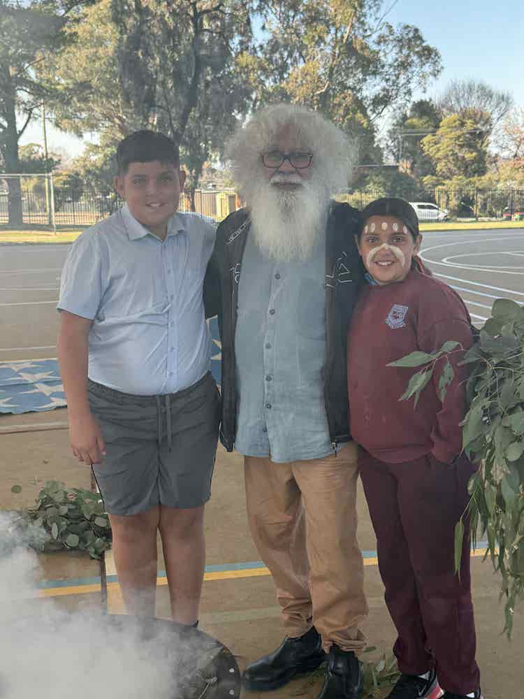 Two students with a local elder celebrating NAIDOC Week.