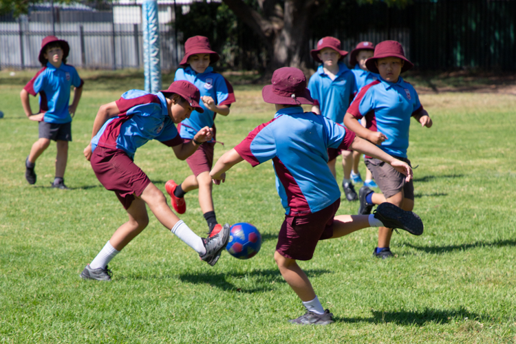 Stage 3 kids playing soccer on the school oval.